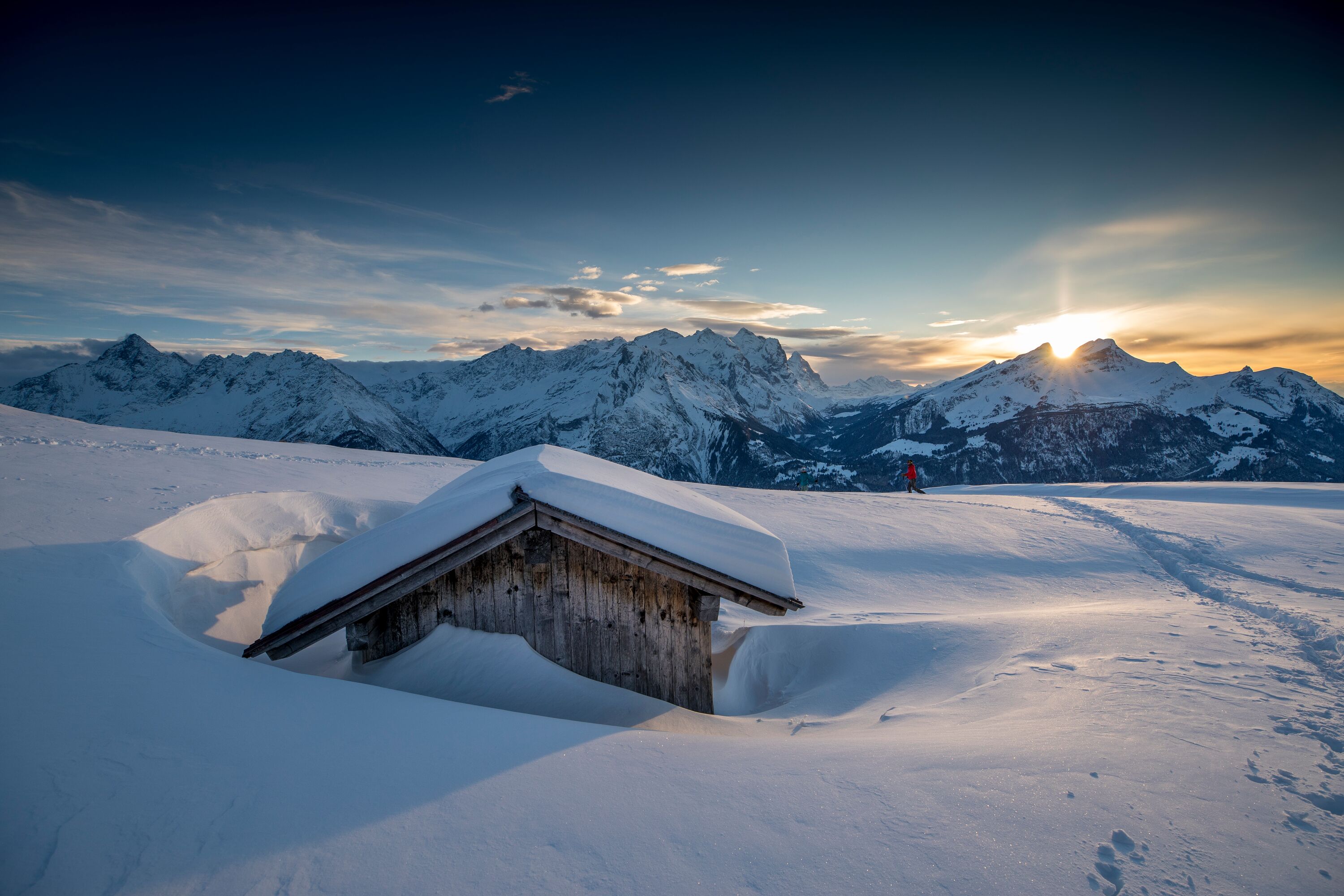 Hasliberg_Winter Ein einsamer Wanderer unterwegs bei Sonnenuntergang in der verschneite Winterlandschaft am Hasliberg